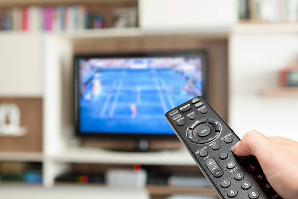 watching clay court tennis with tv remote control in hand similar images: